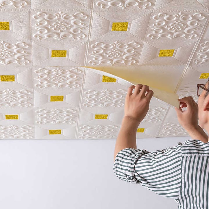 Embossed foam tile being peeled from its backing on a ceiling